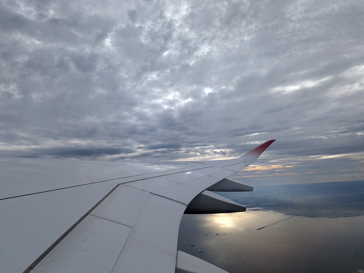 早朝便の窓から見た雲と海、JAL機の翼